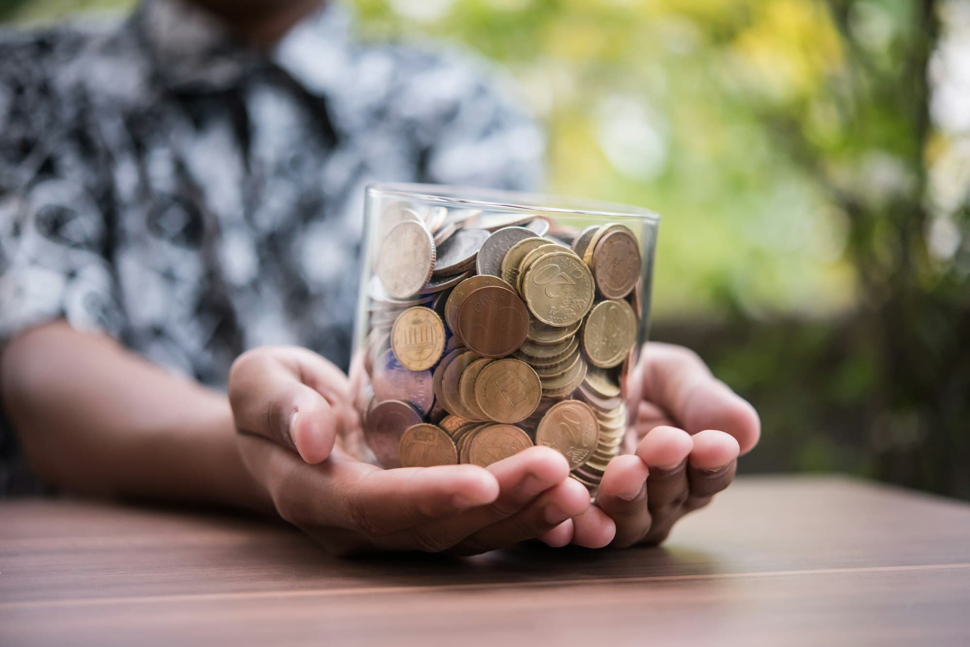 Hand putting coins in jar with money stack step growing growth saving money